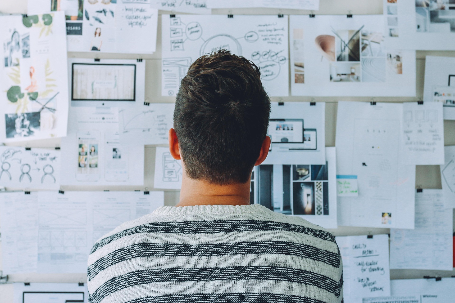 Man reviewing a wall of strategy diagrams and mood board images